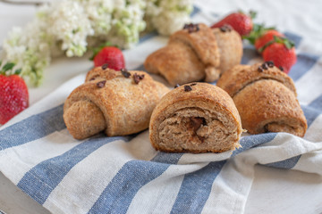 Homemade fresh golden croissants with strawberries and white lilac 