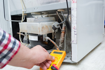  Male Technician Checking Fridge With Digital Multimeter.  Repairman contractor repairing fridge...