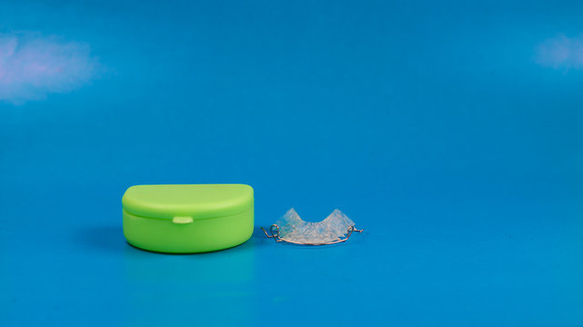 dental retainer with green colored case, blue background.