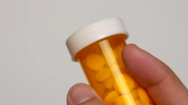 Person puts cap back onto pill bottle.