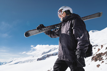Close-up Portrait bearded male skier aged against background of mountains. An adult man wearing ski...