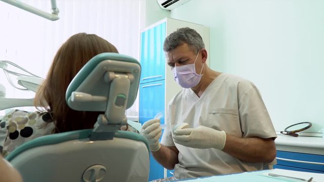 Dentist performing surgery using sterilised equipment. Portrait of a dentist. The patient in the dental chair. Dental care concept. Happy person.