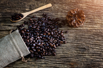Coffee bean in spoon and bag on wood background