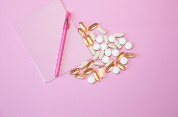 pills, capsules and a notebook with a pen on a pink background, with copy space for text  or image. Flat lay. Top view.