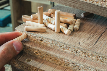 Furniture fittings, wooden dowels, fastener connection on chipboard workpieces, close-up