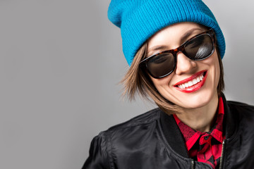  Fashion photo of stylish young woman in jacket, jeans, plaid shirt wearing sunglasses