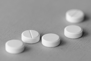White tablets scattered on a gray surface close up. Black and white
