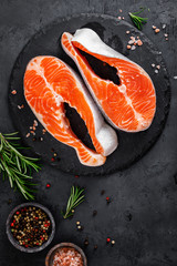 Raw salmon fish steaks on black background