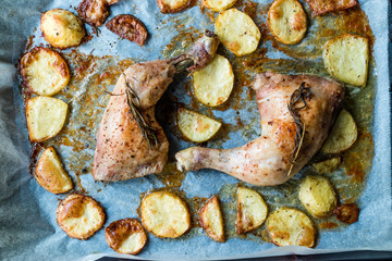 Two Grilled Chicken Legs with Baked Potatoes in Oven Tray.