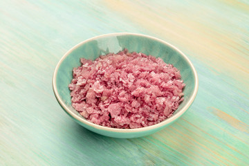 Obraz na płótnie Canvas A bowl of pink Himalayan sea salt on a teal blue background