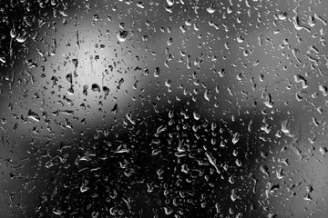 Raindrops on glass in rainy weather close up. Natural background black and white