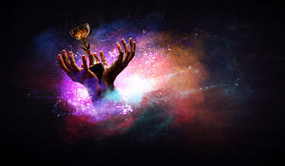 Hands holding champion cup on colourful splashes background. Mixed media