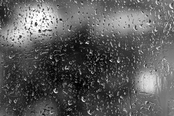 Obraz premium Raindrops on glass in rainy weather close up. Natural background black and white