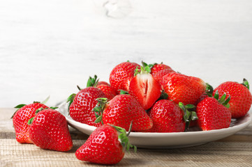 Fresh strawberries in plate on wood