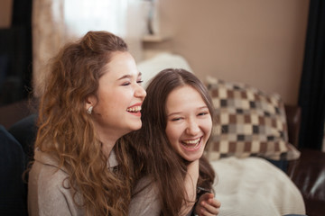 photo of two attractive happy woman friends hugging each other, indoor