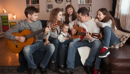 Portrait of a large family, children and parents sing and play the guitar together, indoor