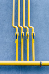 yellow gas pipe with a crane goes along the facade of a new multi-storey building.
