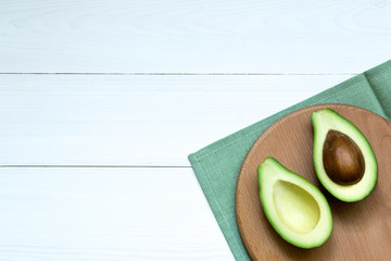 Chopped halves of avocado on a white wooden board, concept background, top view, copy space.