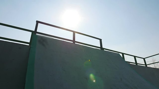 A professional BMX rider in grey hoodie riding down on the ramp in the skatepark