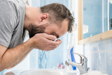 Man washing his face in bathroom