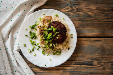 cutlets with pasta on a plate on a wooden background