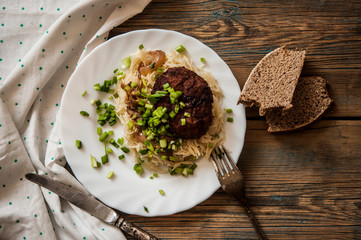 cutlets with pasta on a plate on a wooden background