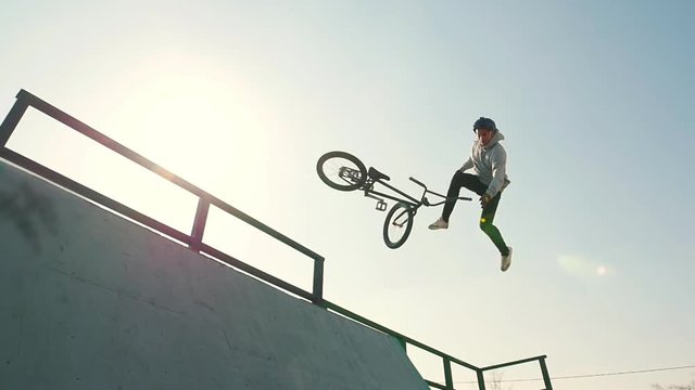 A professional BMX rider in grey hoodie going up on the ramp and performing a trick