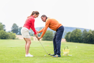 Golfer giving training to woman for taking a shot