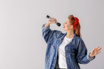 Beautiful female singer with microphone on light background