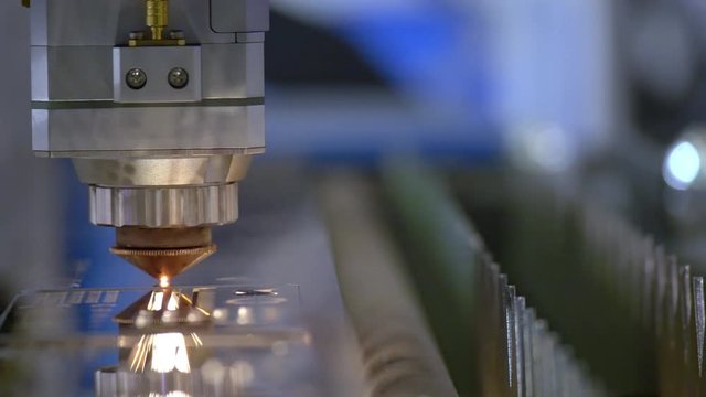 Cutting of metal. Sparks fly from laser. Industrial laser cutter with sparks. The programmed robot head cuts with the aid of a huge sheet of metal temperature