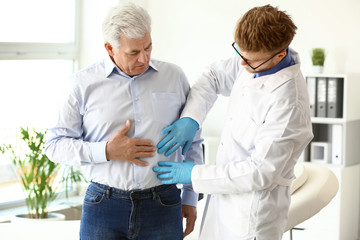 Urologist examining male patient in clinic
