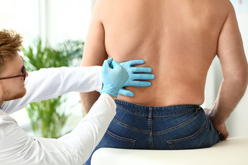 Urologist examining male patient in clinic