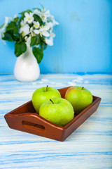 Green apples on a wooden tray.