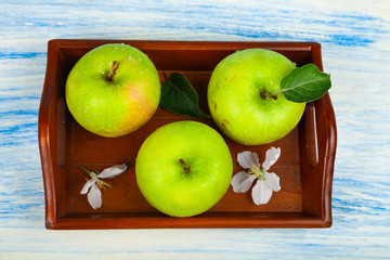 Green apples on a wooden tray.
