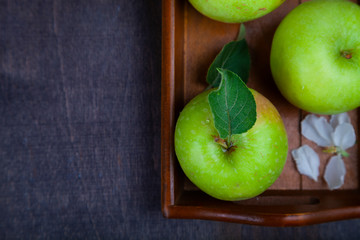 Green apples on a wooden tray.