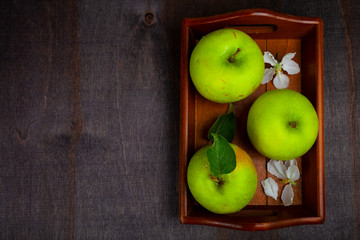 Green apples on a wooden tray.