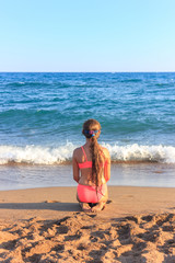 Fototapeta na wymiar Young teen girl sitting on the beach looking to the sea