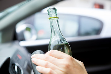 Drunk young driver drinking a bottle of wine during driving the car.