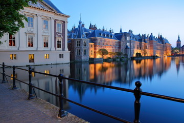 Reflections of the Mauritshuis and the Binnenhof (13 century gothic castle) on the Hofvijver lake during the blue hour, with the clock tower of Grote of Sint Jacobskerk, The Hague, Netherlandsl