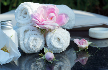 Obraz na płótnie Canvas Set for outdoor spa treatments, folded white towels, soap, lotion and fragrant flowers