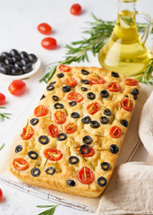 Focaccia with tomatoes, olives and rosemary, vertical. Whole Italian flat bread, bottle with oil