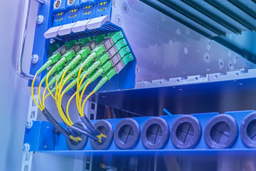 Server with set of green fiber optic cables plug to equipment in data center