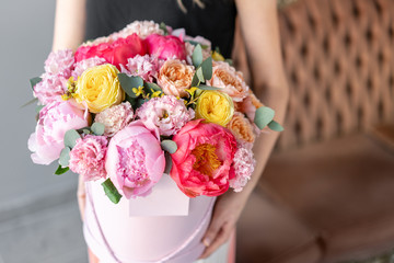 coral and pink peony. Beautiful bouquets of mixed flowers in womans hands. Packed in a round box of hat. Floral shop concept . Fresh cut Flowers delivery