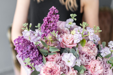 Flower shop. Beautiful bouquet of mixed flowers in woman hand. the work of the florist at a flower shop. Delicate Pastel color. Fresh cut flower. Pink and lilac color