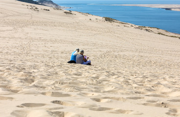A couple of people are resting on the Dune of Pilat, the tallest sand dune in Europe. La Teste-de-Buch, Arcachon Bay, Aquitaine, France