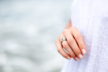 Beautiful woman hand with wedding ring with ocean background. Love concept.