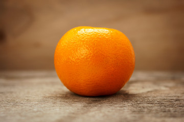 Ripe tangerine on a wooden table on a brown background