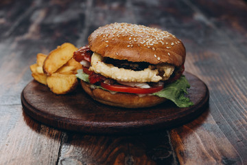 Big tasty burger and fries on background on the wooden table