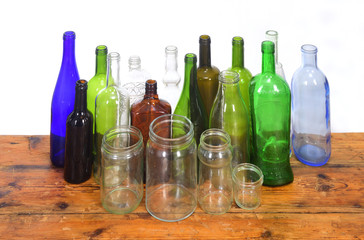 group of bottles and glass jars on a wooden table with white background
