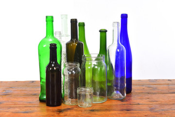 group of bottles and glass jars on a wooden table with white background